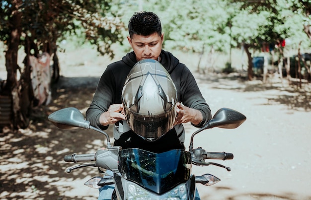 Cz?owiek na motocyklu zakładanie kasku Motocyklista zakładanie kasku Biker koncepcji bezpieczeństwa motocykla Młody mężczyzna motocyklista zakładanie kasku