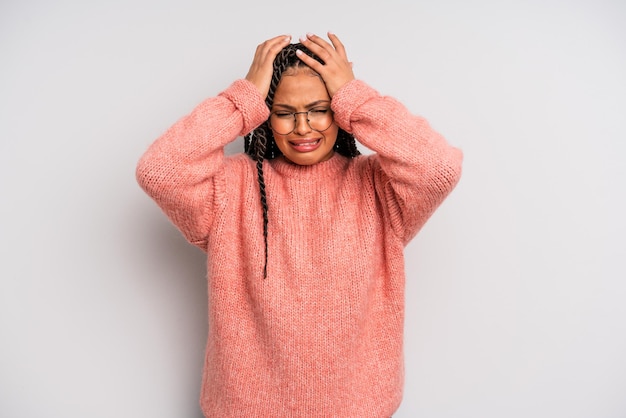 Zdjęcie czarna afro kobieta czuje się zestresowana i niespokojna, przygnębiona i sfrustrowana z bólem głowy, podnosząc obie ręce do głowy