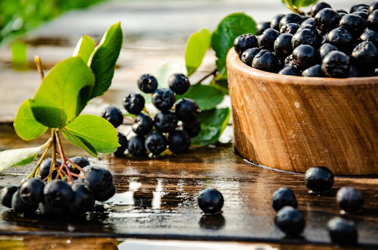 Zdjęcie czarna aronia w drewnianych naczyniach.