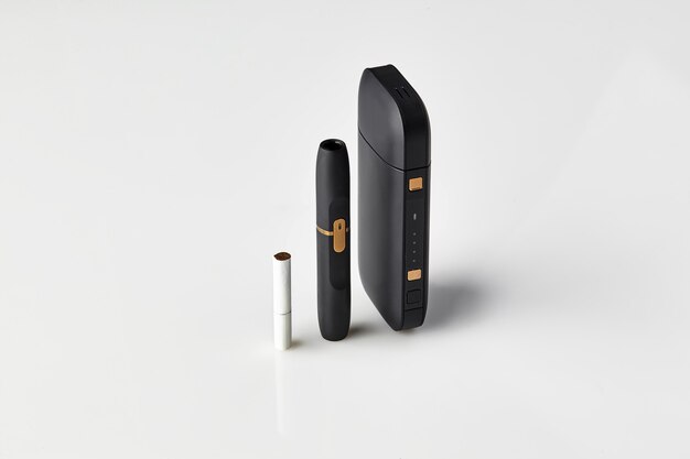 Czarna bateria do papierosów nowej generacji i jedna pałeczka cieplna na białym, hitechowym ogrzewaniu...