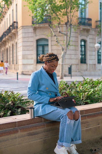 Czarna bizneswoman pracuje zdalnie w parku miejskim z dotykowym laptopem