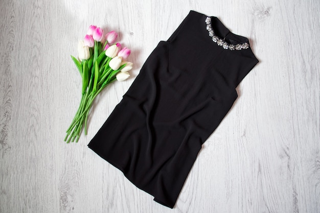Zdjęcie czarna bluzka z kryształkami, różowe tulipany. modna koncepcja, widok z góry