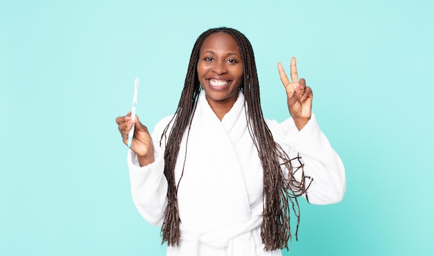 Czarna dorosła kobieta z Afryki, ubrana w szlafrok i trzymająca szczoteczkę do zębów