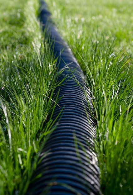 Czarna falista rura plastikowa na zielonej trawie Rury do użytku na zewnątrz Kanalizacja Czarna długa