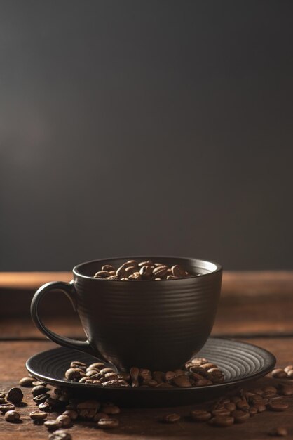 Czarna filiżanka Czarna filiżanka z ziarnami kawy obok niej na rustykalnym drewnianym ciemnym stylu żywności zdjęcie selektywne fokus