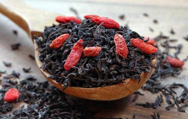 czarna herbata z czerwonymi nasionami w drewnianej misce