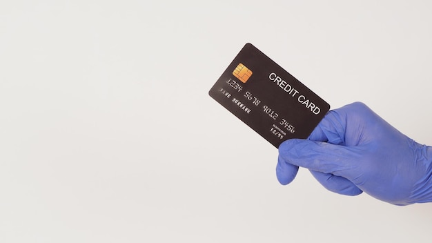 Czarna karta kredytowa w dłoni i nosić fioletową lub fioletową rękawiczkę lateksową na białym tle