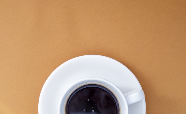 Czarna kawa w filiżance białej kawy na delikatnym tle. Widok z góry, leżał płasko, kopia przestrzeń. Kawiarnia i bar, koncepcja sztuki baristy. Świeżo przygotowana kawa naturalna lub rozpuszczalna w filiżance. Tło kawy.