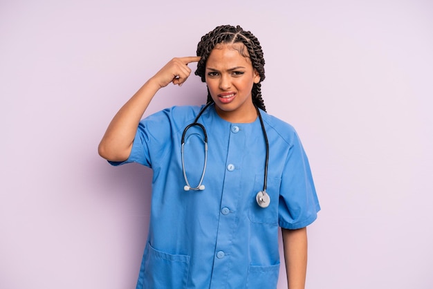Czarna kobieta afro czuje się zdezorientowana i zdziwiona, pokazując, że jesteś szaloną koncepcją pielęgniarki