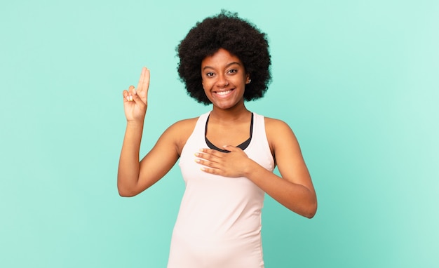 Czarna kobieta afro nosząca ubrania do fitnessu przed odosobnioną ścianą