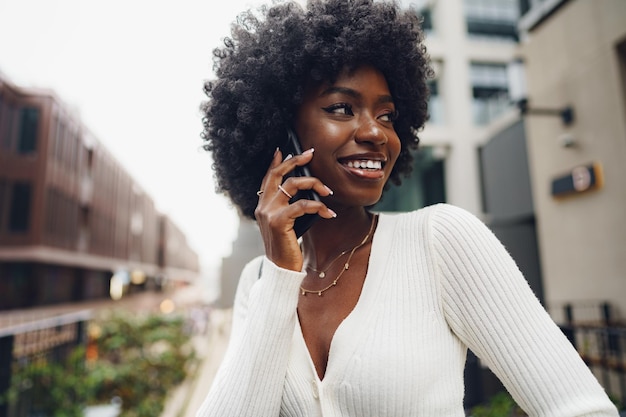 Czarna kobieta afro rozmawia przez telefon komórkowy w mieście