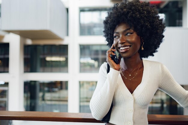 Czarna kobieta afro rozmawia przez telefon komórkowy w mieście