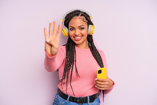Czarna Kobieta Afro Uśmiechnięta I Przyjazna, Pokazująca Numer Cztery. Koncepcja Muzyki Do Słuchania