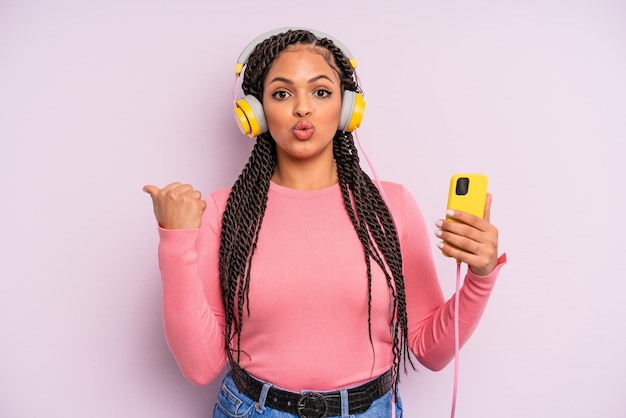 Czarna kobieta afro wyglądająca na zdziwioną koncepcją słuchania muzyki z niedowierzaniem