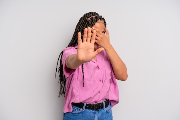 Czarna kobieta afro zakrywająca twarz dłonią i kładąca drugą rękę do przodu, aby zatrzymać aparat odmawiający robienia zdjęć lub zdjęć