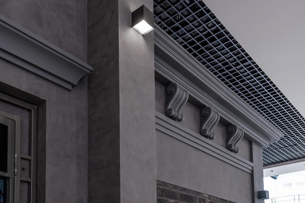 Czarna kolumna we wnętrzu z podwieszanym i siatkowym sufitem z halogenowymi lampami punktowymi i konstrukcją płyt kartonowo-gipsowych w pustym pomieszczeniu w sklepie lub domu Sufit napinany biały i złożony kształt