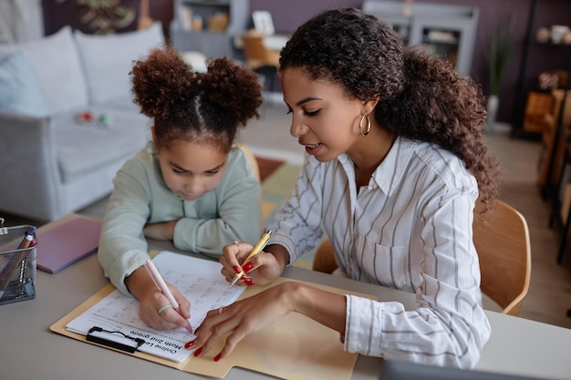 Czarna młoda kobieta wyjaśniająca matematykę małej dziewczynce na lekcji edukacji domowej