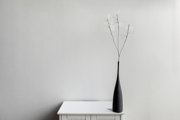 Czarna porcelanowa wazonka na małej białej drewnianej szafce