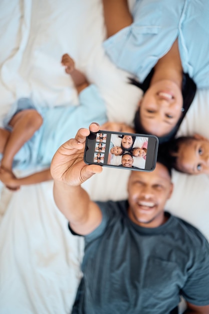 Czarna rodzina szczęśliwa lub selfie przez telefon w sypialni z miłości, zrelaksuj się lub opublikuj w aplikacji społecznościowej w domu Portretowe zdjęcie rodzinne lub rodzice i dzieci na łóżku z technologią smartfona lub widokiem z góry ekranu