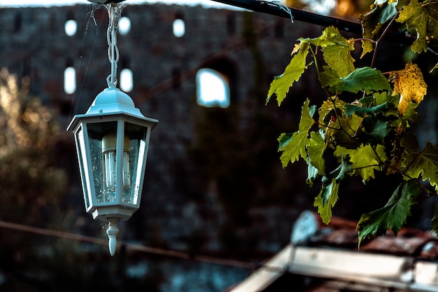 Czarna stara rocznik lampa na ściana z cegieł z dekoracyjnymi świeczkami inside przy starym grodzkim domem