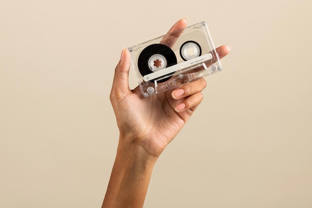 Czarna żeńska ręka pokazuje zwykłą kasetę magnetofonową