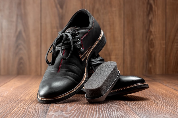 Czarne buty jedną czystą sekundę brudzą i szczotkują na drewnianej ścianie. Pojęcie połysku obuwia, pielęgnacji odzieży, usług.