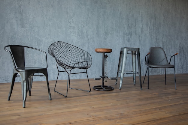 czarne designerskie krzesła na drewnianej podłodze przy szarej ścianie botanicznej