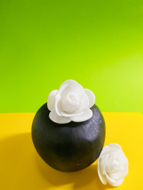 Czarne jabłko z białymi kwiatami na tle kolorowego papieru Abstrakcja symbolizuje wykwintne jedzenie
