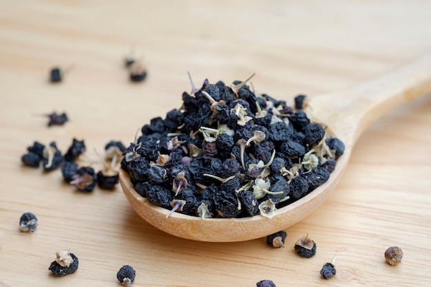 Czarne jagody goji lub czarne jagody goji, w drewnianą łyżką na stole. Zioła chińskie powszechnie stosowane w tradycyjnej medycynie chińskiej. Pojęcie opieki zdrowotnej.
