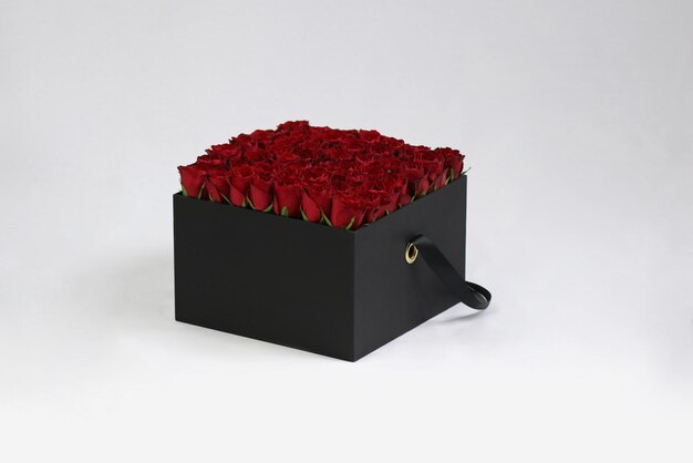 Czarne kwadratowe pudełko na prezent z czerwonymi różami w środku