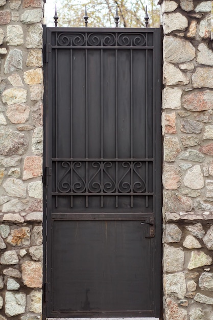 Czarne metalowe drzwi z kamienną ścianą. Antyczny wygląd architektury miejskiej