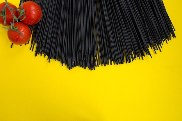 Czarne spaghetti i wiśnia na żółtym tleWidok z górySkopiuj miejsce