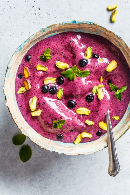 Czarnej jagody smoothie puchar z pistacjami i mennicą na białym tle, odgórny widok