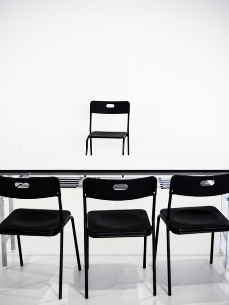 Czarni krzesła z bielu stołem na białym tle. Koncepcja miejsca wywiadu