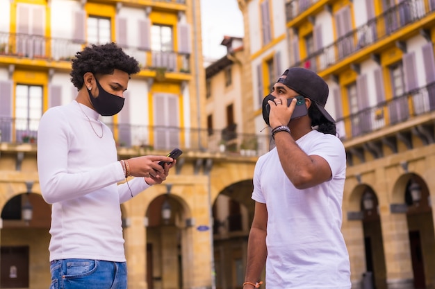 Czarni przyjaciele Latino rozmawiają przez telefon z maską.