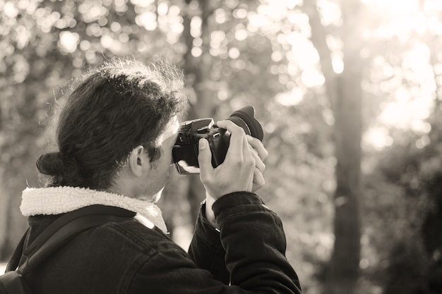 Czarno-białe zdjęcie fotografa w jesiennym parku fotografowania jesiennych krajobrazów. Koncepcja fotografa