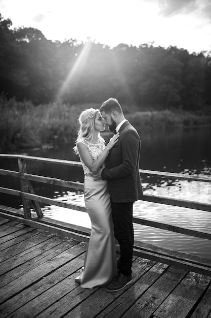 Zdjęcie czarno-białe zdjęcie stylowa para nowożeńców pozujących na moście w dniu ślubu