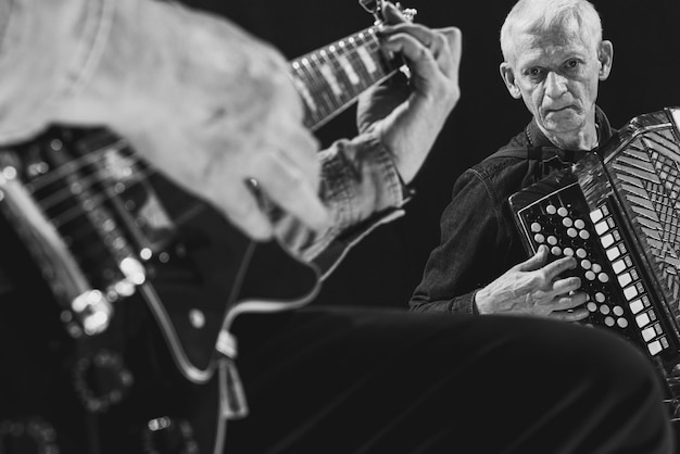 Czarno-biały Obraz Starszych Mężczyzn Grających Na Gitarze I Akordeonie Tworzących Piękną Muzykę