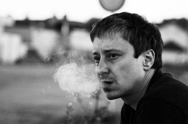czarno-biały portret mężczyzny, który wydycha dym