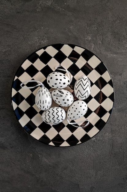 Czarno-biały talerz z kolorowymi jajami na konkretnym tle Tło karty wielkanocnej