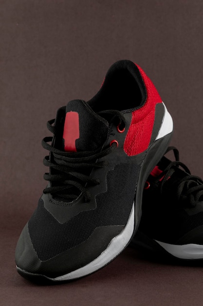 Czarno-czerwone sportowe buty do tenisa na brązowym tle z miejscem na tekst