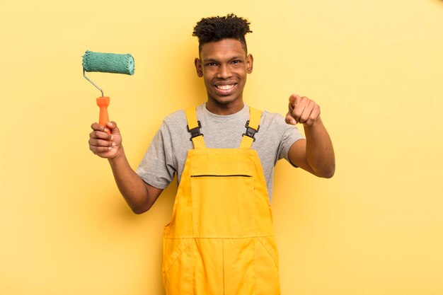 Czarny afro młody mężczyzna wskazujący na aparat wybierający cię gospodyni malująca dom