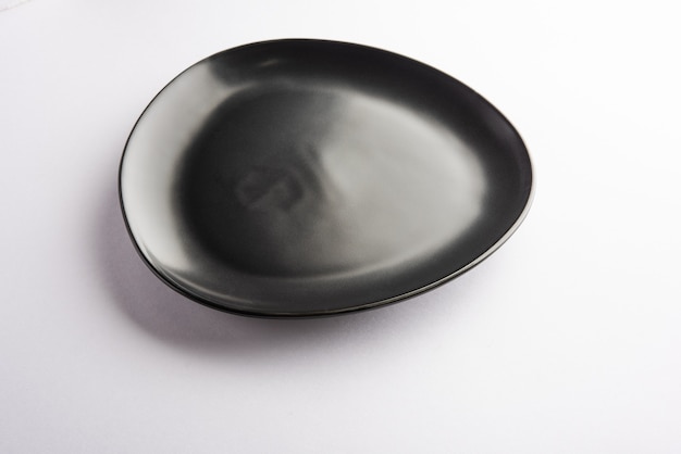 Czarny ceramiczny talerz w kształcie pustego trójkąta na białym tle