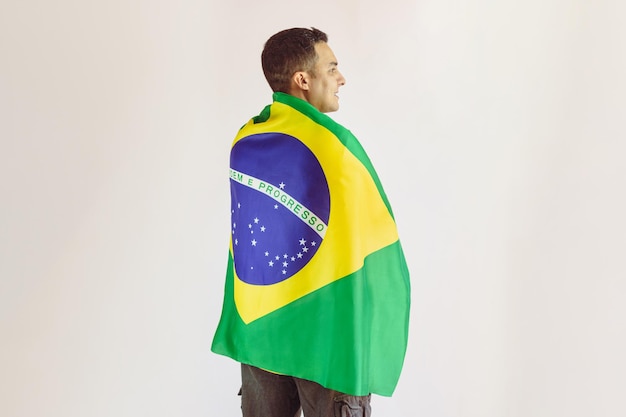 Czarny człowiek trzyma brazylijską flagę z żółtą koszulką drużyny piłkarskiej na białym tle