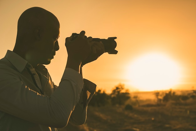 Czarny fotograf fotografuje przy zmierzchem z kopii przestrzenią.