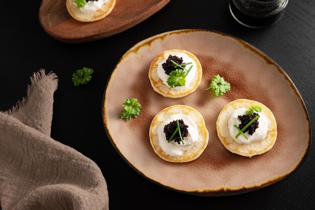 Zdjęcie czarny kawior z jeseterów podawany na mini naleśnikach jako przysmak z produktów rybnych