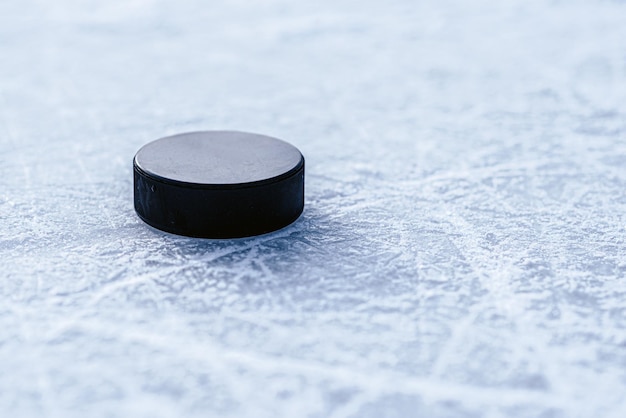 Czarny krążek hokejowy leży na lodzie na stadionie