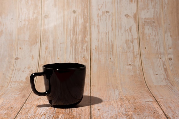 Czarny kubek filiżanka kawy na drewnianym tle