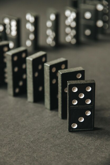 Czarny łańcuch Domino Na Ciemnym Tle Tabeli. Koncepcja Efektu Domina
