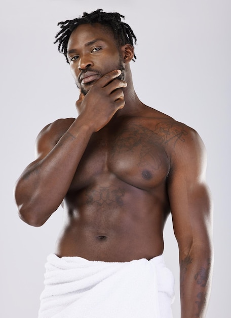 Czarny mężczyzna w ręczniku i mięśniach pod prysznicem portretowym z higieną i pięknem na białym tle na tle studia Abs fitness i wellness twarzy pielęgnacja skóry blask i pielęgnacja ciała za pomocą naturalnych kosmetyków